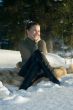 Young smiling girl sitting on snow in wood.