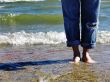 Wet bare feet standing on beach.