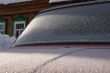 The car covered with frost, against the old wooden house.