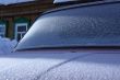 The car covered with frost, against the old wooden house.