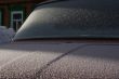 The car covered with frost, against the old house.