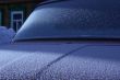 The car covered with frost, against the old wooden house.