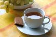 Cup of tea with a piece of biscuit and grapes.