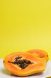 Two halves of papaya on yellow