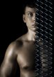 Muscular man behind a lattice