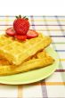 Waffles and strawberries on green plate
