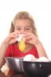 little girl cracking an egg over bowl