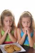 two girls praying over cookies