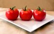 3 red vine ripened tomatoes on a white plate.