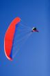a paraplane flying high up in the deep blue sky