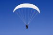 a paraplane flying high up in the deep blue sky