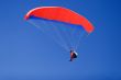 a paraplane flying high up in the deep blue sky