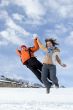 Couple jump over blue sky in winter