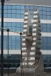 sculpture of modern berd on bridge near glass building