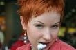 red haired woman wih spoon is smiling in cafe