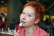 red haired woman wih spoon is smiling in cafe