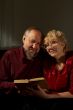 Happy elderly spouses behind reading