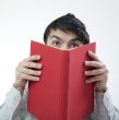 Man hiding his face with book