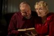 Happy elderly spouses behind reading