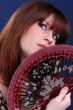 Cute young lady hiding behind fan