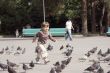 Beautiful girl running at city square and pigeons