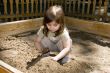 Child girl plaing at sand-box in summer park