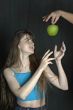 Women extends hands to apple.