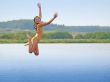 Girl jumping above water smooth surface