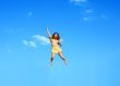 The happy jumping girl on a background of the blue sky