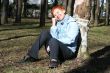 red haired woman is sitting near tree