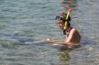 Young woman sitting in water with snorkel and fins