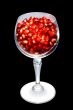 Pomegranate grains in a glass. Isolated on black.