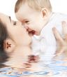 happy mother kissing baby boy in water