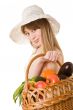 An attractive young woman holding a basket of delicious fresh vegetables. Isolated on white.