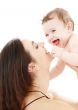 laughing blue-eyed baby playing with mom
