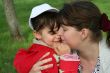 little girl with her mother in the spring park kissing