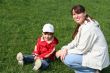 little girl with her mother in the park sitting on green grass