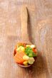 cooked carrots sweet corn and broccoli in a wooden spoon