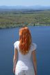 Red-haired girl looking over blue lake