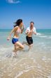 couple racing on the beach with joy