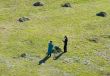 Two people mow a grass
