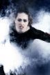 Woman with long curly hair crawling out of smoke