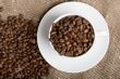 Cup with freshly roasted coffee beans on sackcloth