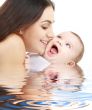 playful mama with happy baby in water