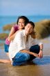 young couple squating by the beach happily