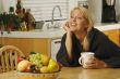 Woman with Cup of Coffee in Kitchen Smiling