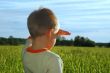 young boy looking  and dreaming on green field