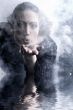 Woman with long curly hair blowing smoke