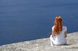 Red-haired girl looking over blue water