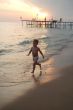 happy young boy running on the beach at sunset